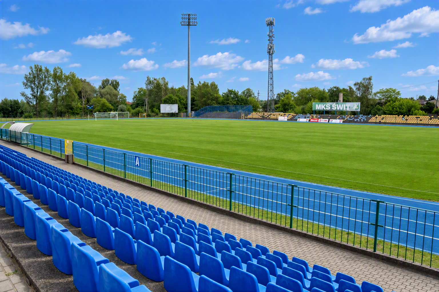 Widok stadionu z trybun na boisko piłkarskie otoczone niebieską bieżnią lekkoatletyczną.